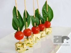 small appetizers with tomatoes and cheese on toothpicks are arranged on a white plate