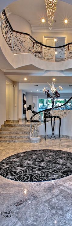 an elegant foyer with marble floors and chandelier above the stairs is pictured in this image