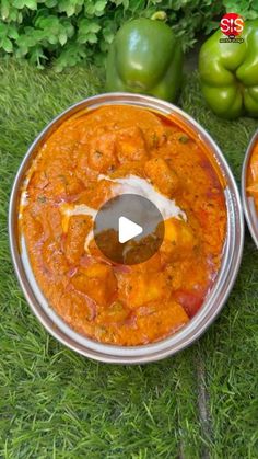 two metal pans filled with food sitting on top of green grass next to peppers