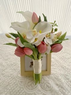 a bouquet of tulips and other flowers in a vase on a white tablecloth