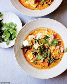 two white bowls filled with soup on top of a table