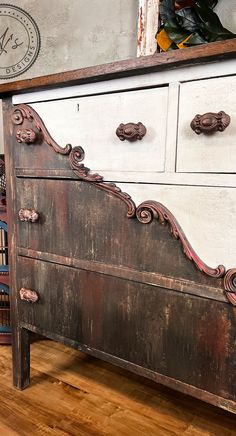 an old wooden dresser with ornate carvings on the top and bottom, sitting on a hard wood floor