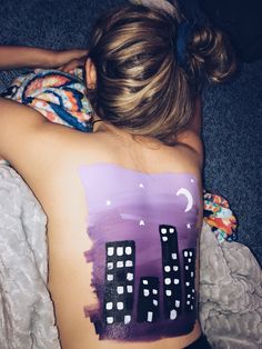 a woman laying on top of a bed with her back turned to the camera and painted