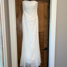 a white wedding dress hanging on a door