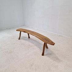 a wooden bench sitting on top of a white floor next to a wall and window