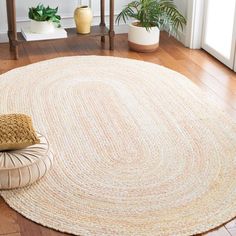 a round rug on the floor in a living room with potted plants and other decor