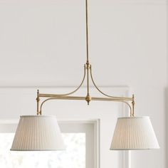 two lamps hanging from the ceiling in a room with white walls and windows behind them