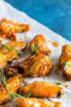 chicken wings covered in sauce and garnished with fresh herbs on a piece of parchment paper