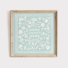 a blue and white framed print with the words home sweet home written in floral designs