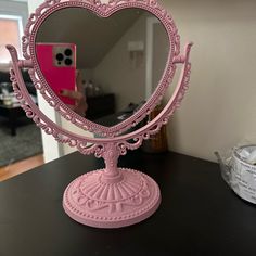 a pink heart shaped mirror sitting on top of a table