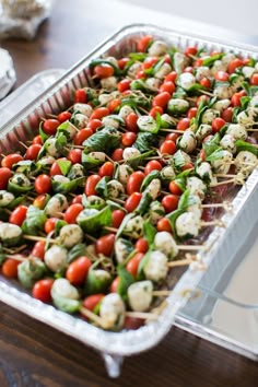 a tray filled with skewered vegetables on top of a wooden table