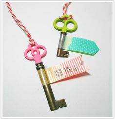 three different colored keys attached to each other on a white surface with red and green twine