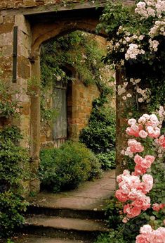 an arch in the middle of a garden with pink and white flowers on either side