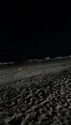 a person standing on top of a sandy beach at night