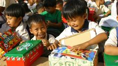 several children are sitting in front of boxes with candy on them and one boy is holding the box