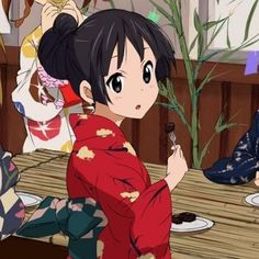 a woman in a kimono eating food at a table