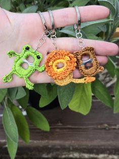 three crocheted keychains in the palm of a person's hand