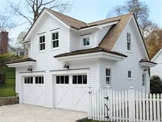 a large white house with two garages on the front and one above it's doors