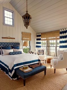 a bedroom with blue and white bedding, two chairs and a lamp hanging from the ceiling