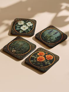 four square coasters with flowers painted on them