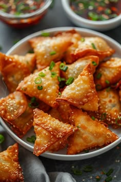 Plate of crispy wontons garnished with chopped green onions, with dipping sauces in the background. Hamburger Wanton, Fried Chicken Wontons, Wonton Egg Rolls, How To Cook Wontons, Fried Wontons Recipes, Crispy Wonton Recipes, Air Fry Appetizers, Appetizer Recipes With Wonton Wrappers, Wonton Chips In Air Fryer