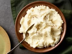 mashed potatoes in a brown bowl with a fork on the plate next to it