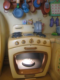 a stove top oven sitting inside of a kitchen next to a wall with pots and pans on it