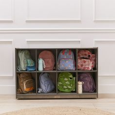 an assortment of backpacks sitting on top of a shelf in front of a wall