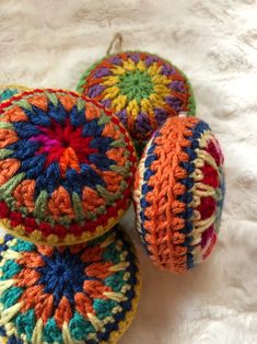 three crocheted balls sitting on top of a white blanket next to each other