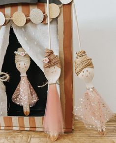 two wooden dolls are hanging from strings in front of a photo frame that is decorated with polka dots and twine