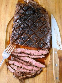 sliced steak on cutting board with knife and fork