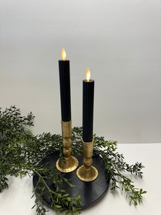 two candles are sitting on a black plate