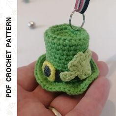 a crocheted green hat is being held in someone's hand with a ring on it