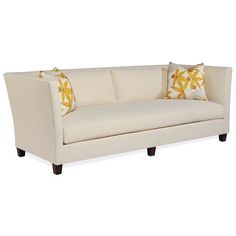 a white couch with two pillows on it's back and yellow flowers on the pillow