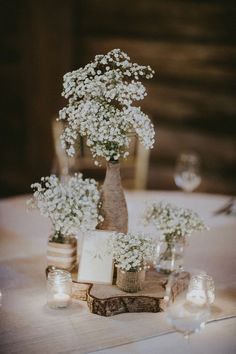 small white flowers are in vases on a table