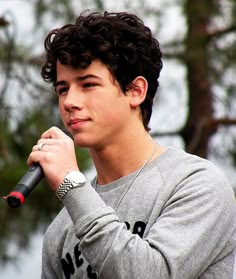 a young man holding a microphone in his right hand