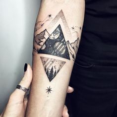 a woman's arm with a mountain and stars tattoo on the left side of her arm