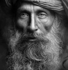 an old man with a long beard wearing a turban and looking at the camera