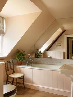 an attic bathroom with white walls and wood flooring, along with a large tub in the corner