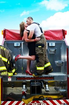 a man and woman kissing on the back of a fire truck