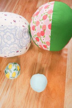 three different colored balls sitting on top of a wooden floor next to each other,