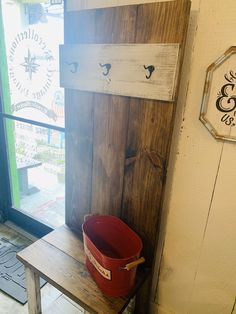 a red bucket sitting on top of a wooden bench next to a sign and window