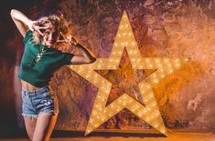 a woman standing in front of a large star with lights on it's sides