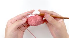 two hands are working on a crochet ball