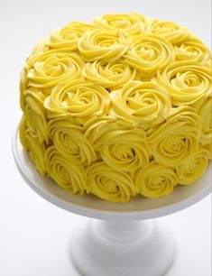 a cake with yellow icing is on a white plate and sits on a pedestal