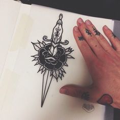 a person with tattoos on their hands holding up a tattoo design that looks like a sunflower