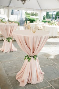 the tables are covered with pink cloths and green leaves on them for an elegant look