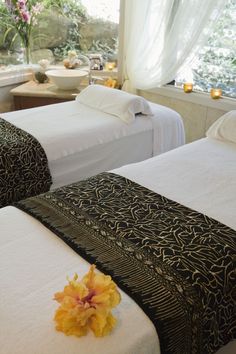 two beds in a hotel room with flowers on them