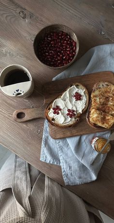 a wooden table topped with bread and cranberries next to a cup of coffee