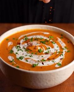 a white bowl filled with carrot soup on top of a wooden table